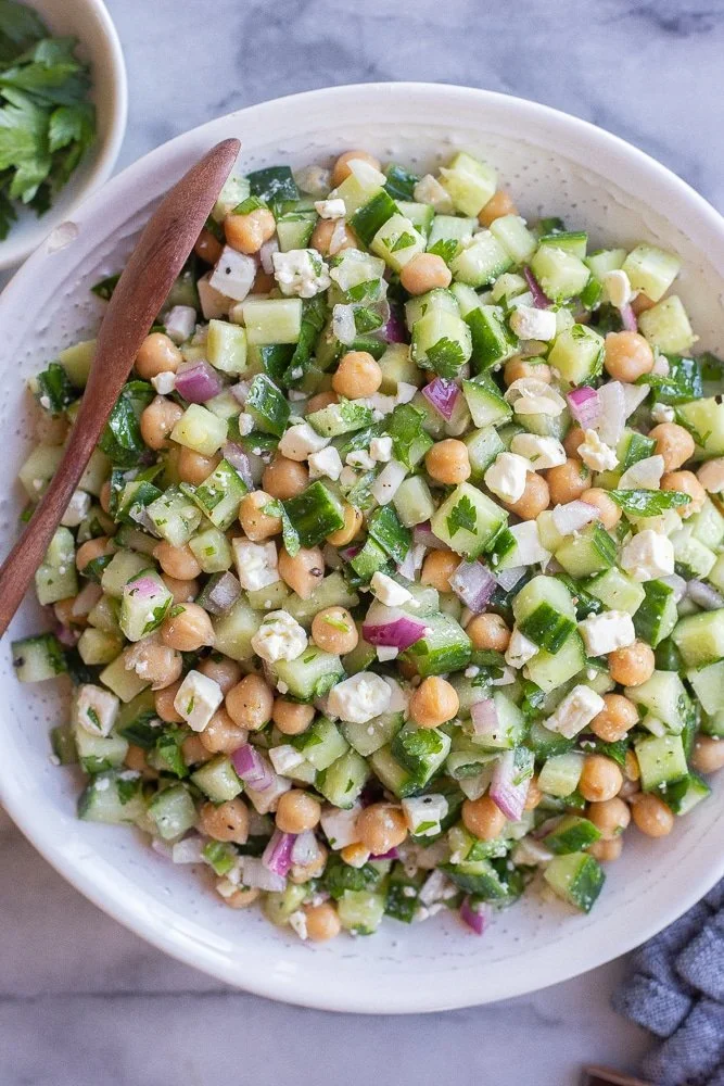 Herby cucumber salad with feta cheese and chickpeas in a bowl.