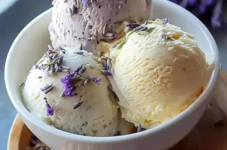 A scoop of honey lavender ice cream in a waffle cone garnished with lavender sprigs.