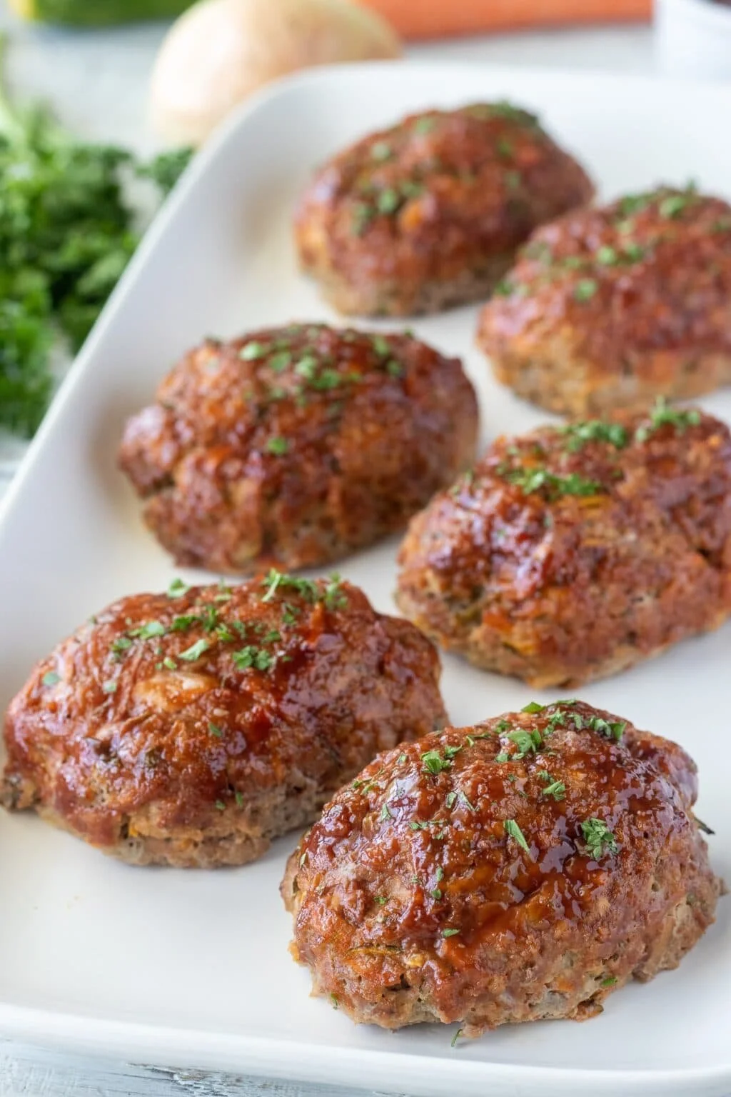 Mini turkey meatloafs served on a plate with fresh herbs