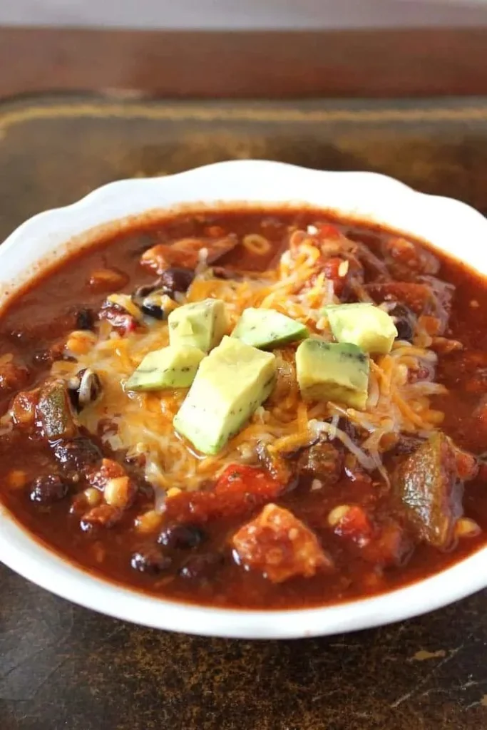 Healthy Skinny Crockpot Chicken Chili in a bowl with ingredients surrounding it.