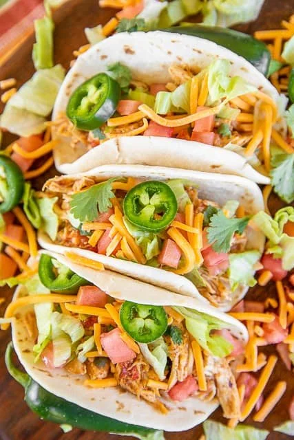Slow cooker queso chicken tacos topped with fresh ingredients
