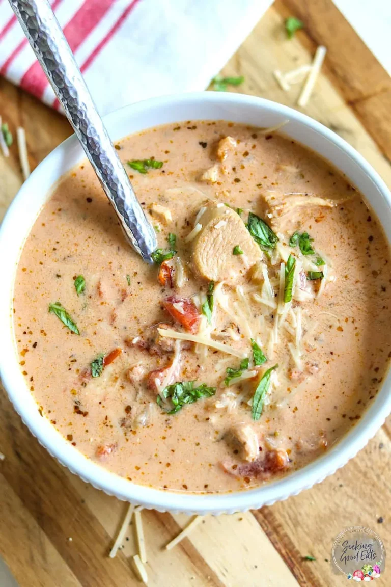 Bowl of sun-dried tomato soup with pieces of chicken and garnished herbs