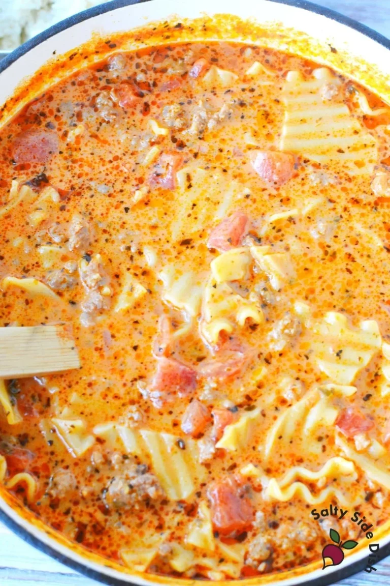 Delicious cheesy lasagna soup with sausage in a bowl, topped with fresh herbs.