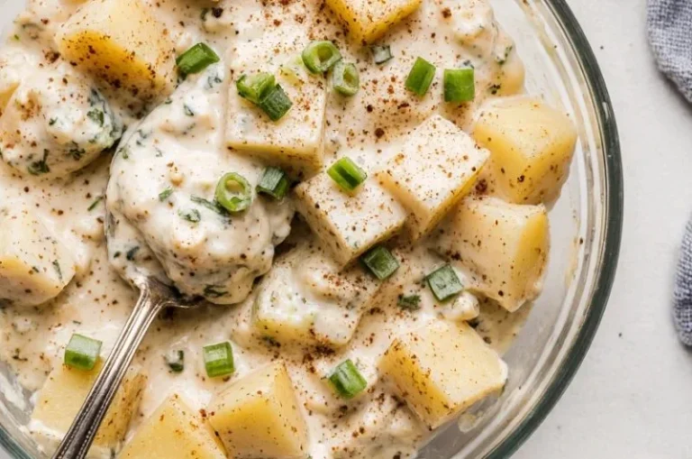 Bowl of classic creamy potato salad garnished with herbs