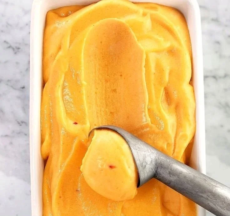 Bowl of homemade peach sorbet with fresh peach slices on top