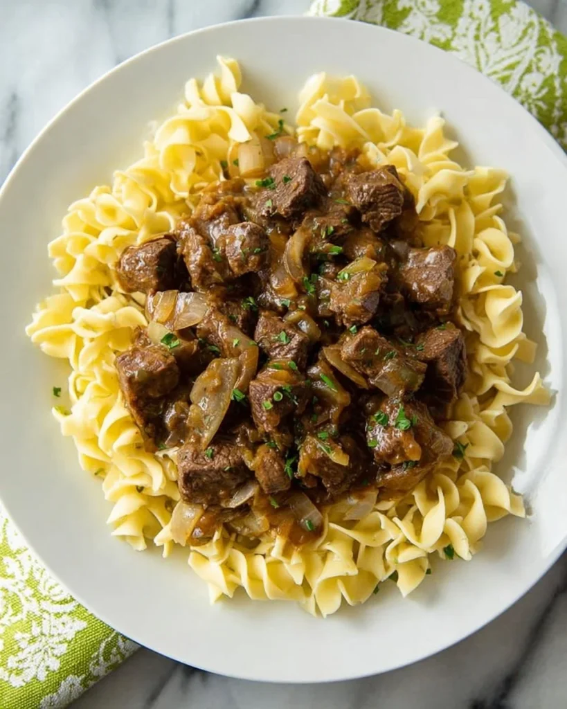 A delicious bowl of Slow Cooker Amish Beef and Noodles served with herbs